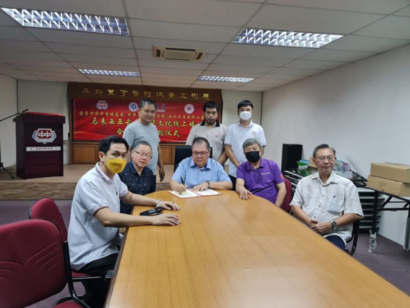 古晋中华中学校友会会长拿督黄国辉（坐者中）在副会长张光福（右一）、副会长许庆喜（右二）、副会长兼中青团团长陈明（左一）、秘书长田荣喜（左二）陪同进行线上签约。