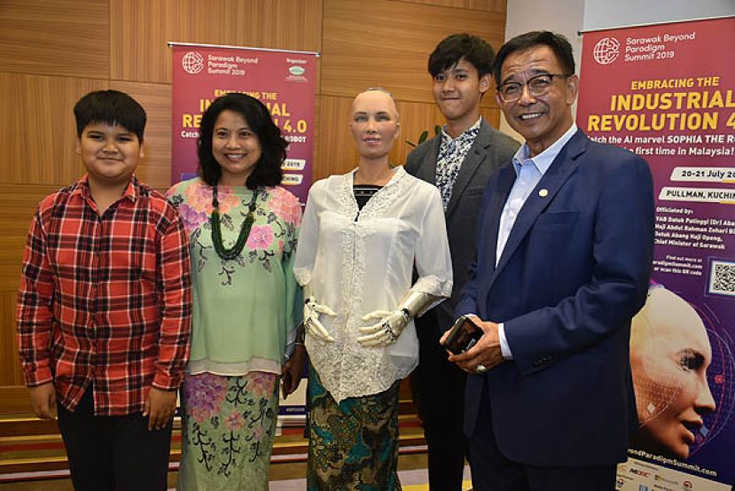 砂旅游、艺术、文化、青年与体育部长拿督阿都卡林(右一)与家人和机械人索菲亚合照。