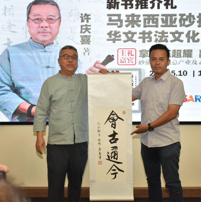 许庆喜硕士(左)赠送书画纪念坡予古晋中华中学校友会会长拿督黄国辉的代表邓守志(右)。