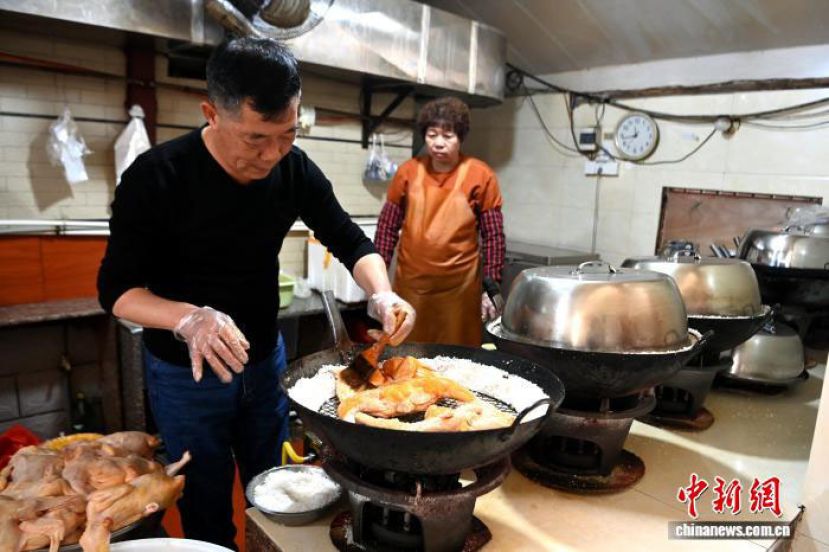 闽南盐鸡传统制作技艺代表性传承人蔡建民，将传统秘制酱汁涂抹在处理好的鸡全身，撒上秘制盐焗粉。