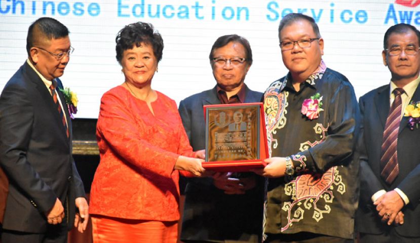 砂首长拿督巴丁宜阿邦佐哈里(中)见证下,黄文彬集团董事拿督黄国辉(右二)颁发丹斯里拿督阿玛黄文彬精神奖(华社服务奖)予甲必丹李碧贞。左一为晋汉连省华总会长拿督黄良杰,右一为晚宴筹委会主席郑文新。