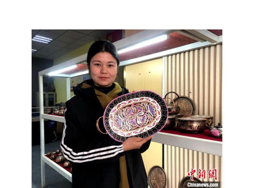 迪丽努尔·艾则孜展示镶有艾德莱丝绸花纹的托盘。