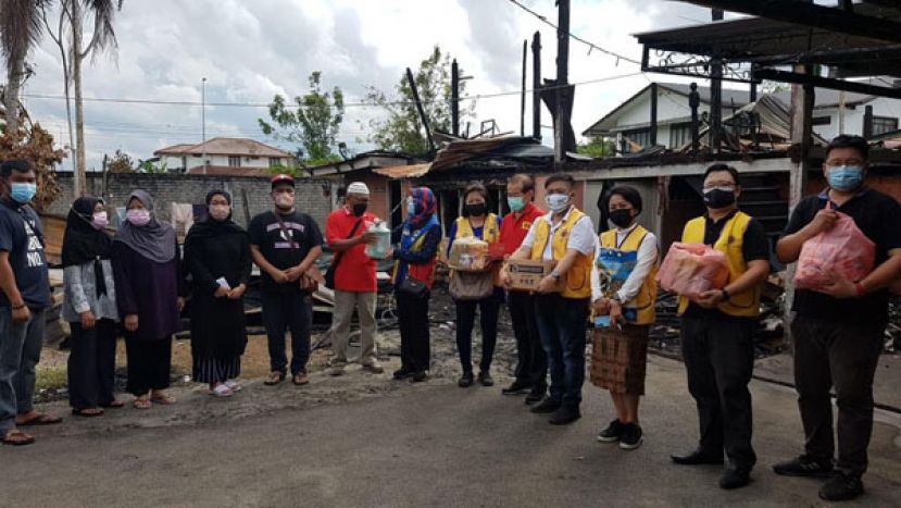 一行人移交捐款和日用品予火患灾民。右三为哥打圣淘沙獅子会会长邓昭桦、艾索拉獅子会会长许統业（右四）、哥打圣淘沙獅子会前  会长张南华 （右五）、百年狮子会会长余小莉（右六）及国际狮子会前理事拿汀依丽絲苏里亚蒂（右七）。