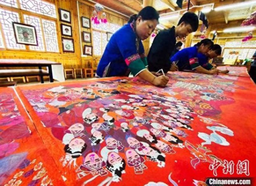 在广西三江侗族自治县民族实验学校农民画工作坊，当地农民画家正在集体创作农民画长卷作品。