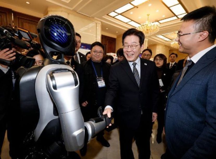 李在明与中国生产的机械人握手。