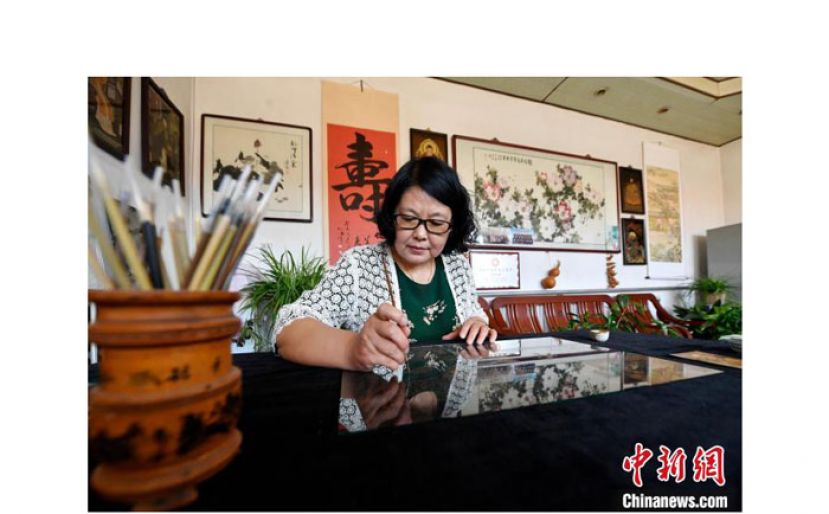 裴小苓在家中伏案绘制玻璃油画。