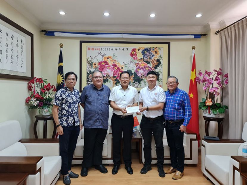 筹委会主席张职程（右二）将邀请函移交予中国驻古晋总领事邢伟平（中），左二为古晋中中校友会会长拿督黄国辉、左一为副会长曾应华，右一为秘书长田荣喜。