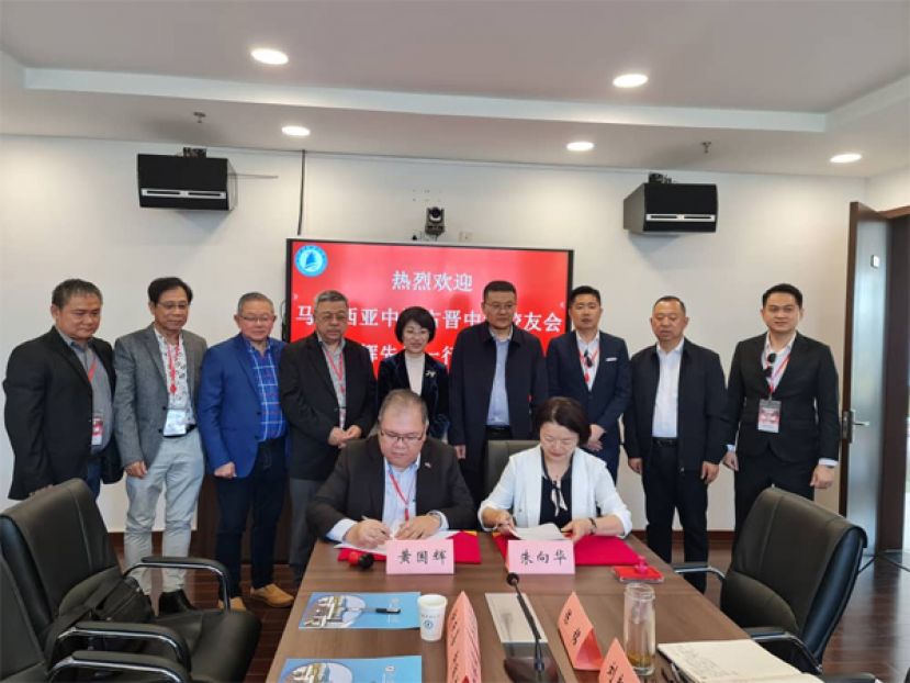 江苏科技大学海外学院书记朱向华教授（右）与中中校友会会长拿督黄国辉（左）签署合作协议。见证者为施伟东副校长（右四）、校常委刘新波（右二）、镇江市侨联副主席黄蓓（左五）。