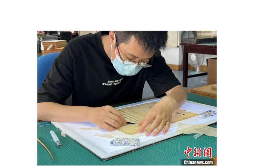 薛继民正在修复古籍。