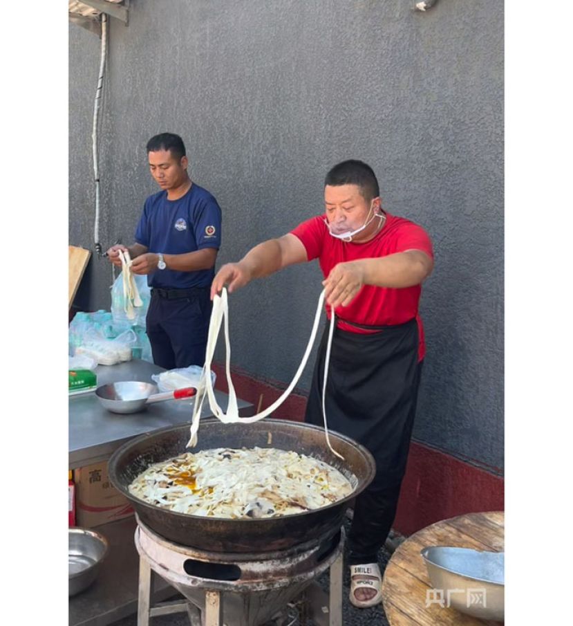 赵占胜（右）正在为村民煮烩面。